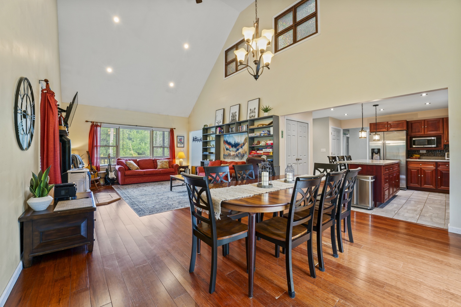 Open great room with vaulted ceiling, dining table, living area, and kitchen