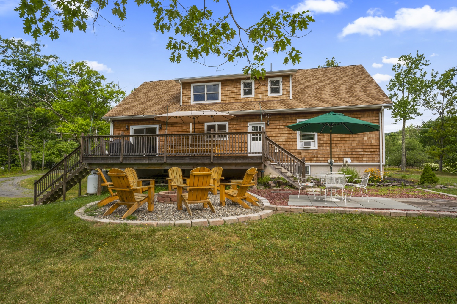 Rear of the house with deck, fire pit, patio, and large lawn