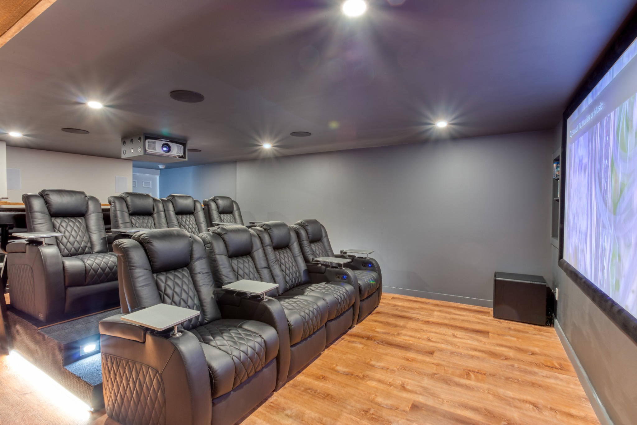 Private 4K home theater with two rows of powered recliners and the movie screen